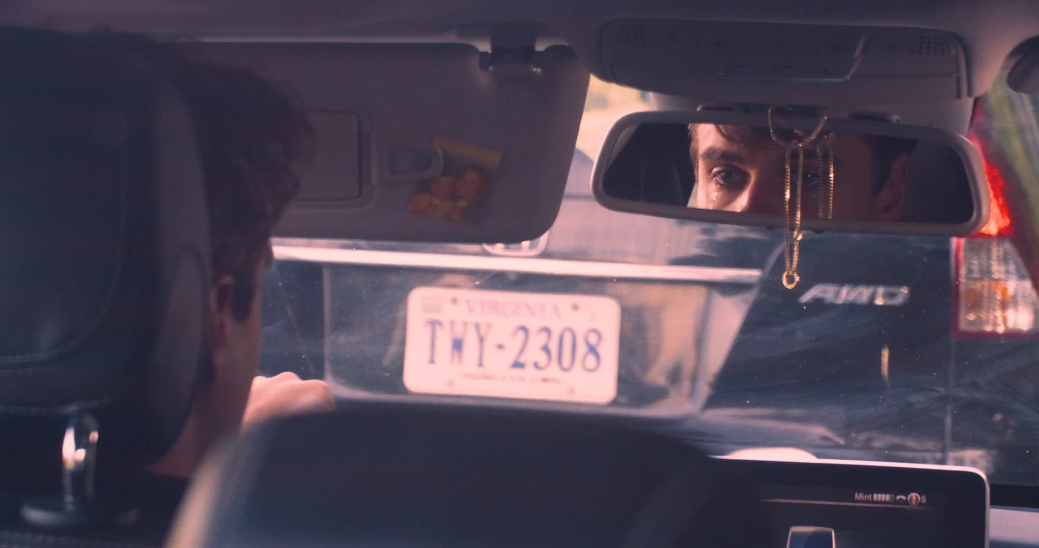 A tearful eye reflected in a rearview mirror