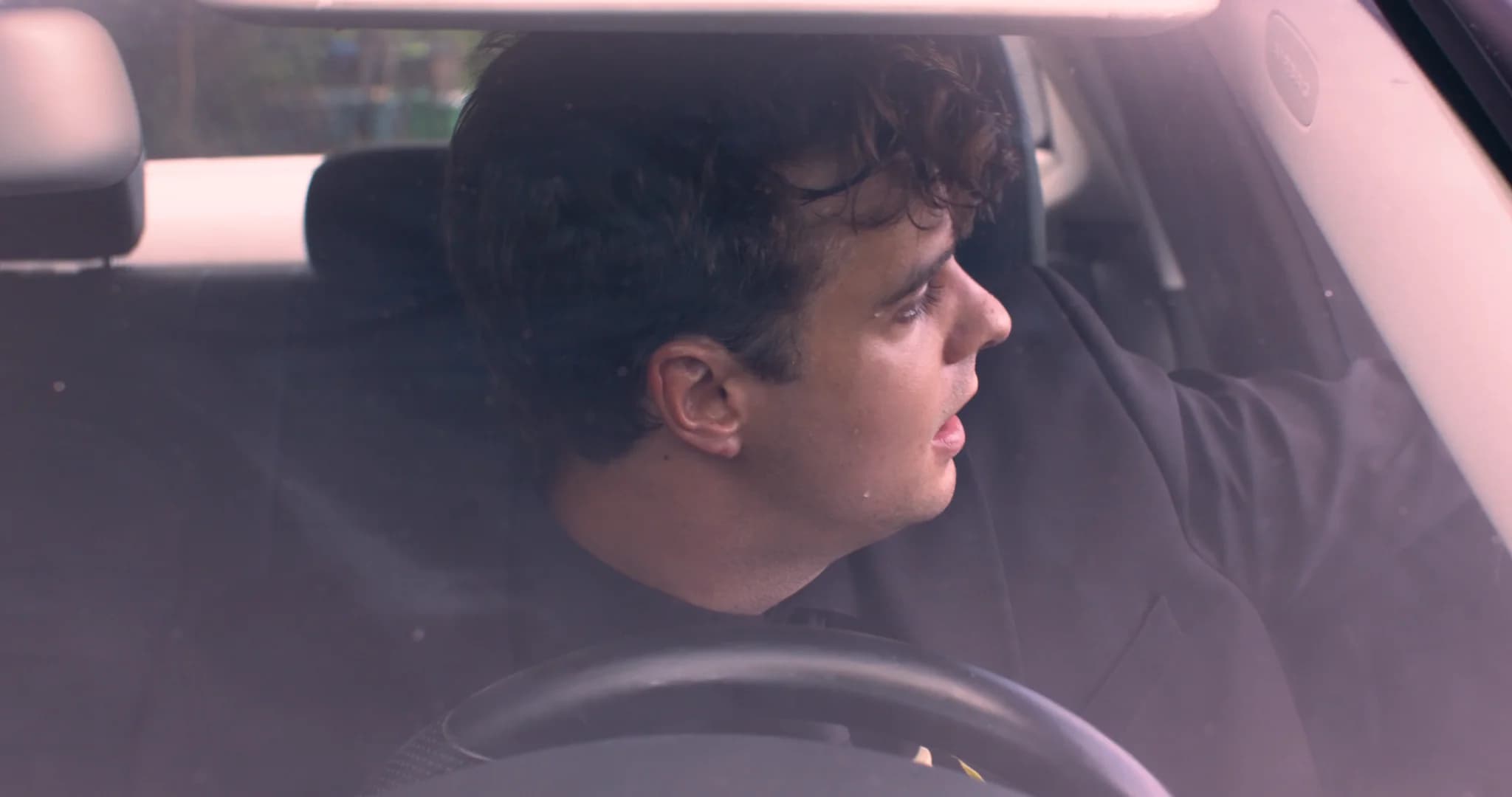 A man in a dark suit sitting inside a car